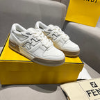 White low-top unisex sneakers with tan logo panels and lace-up front.