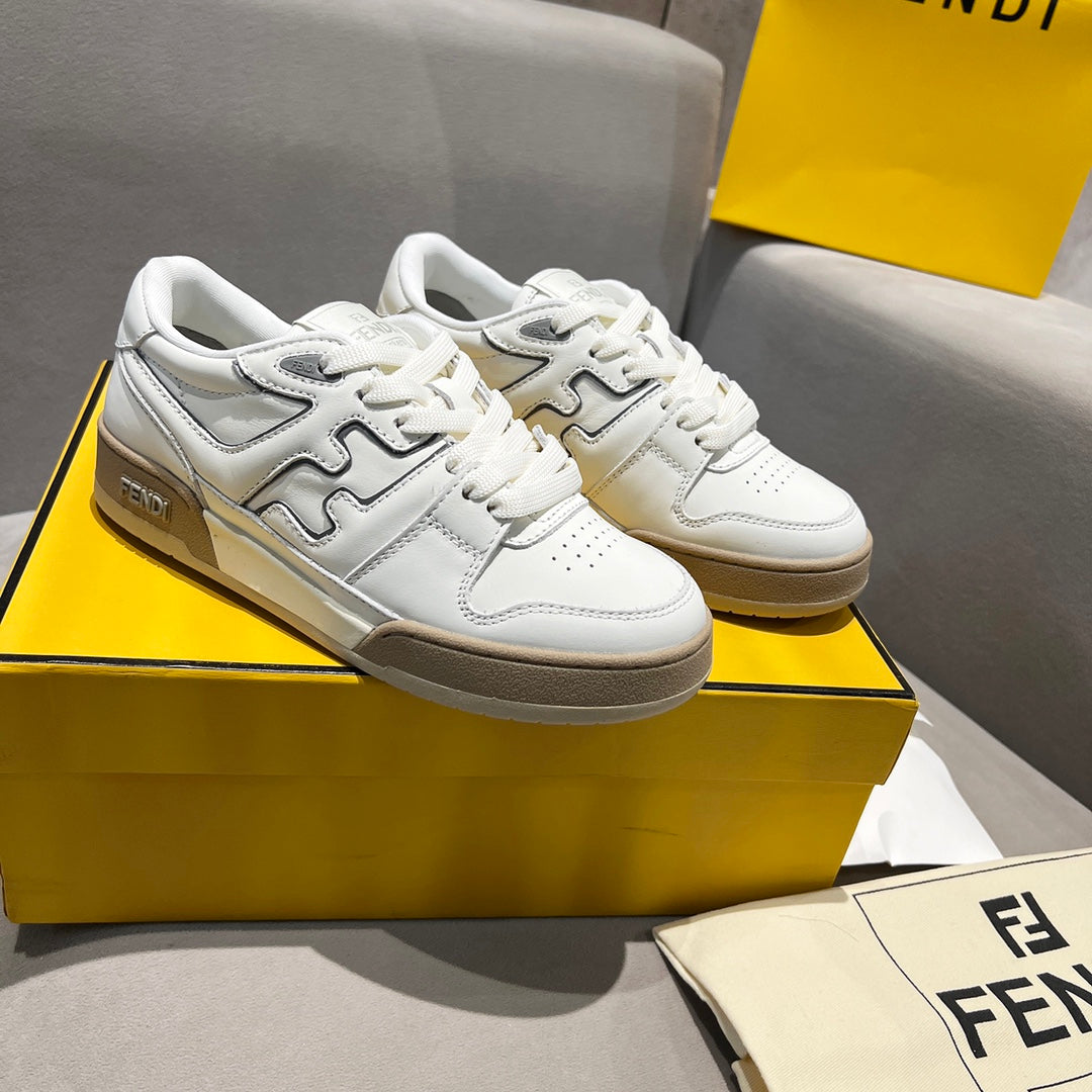 White low-top unisex sneakers with tan logo panels and lace-up front.
