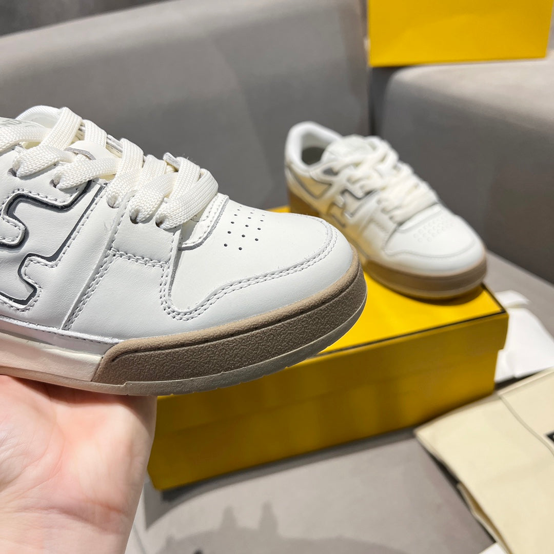 White unisex sneakers with chunky dark rubber sole and lace-up closure.