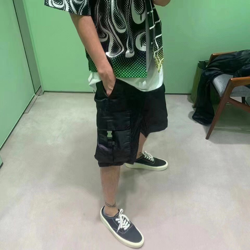 Black cargo shorts with layered pocket panels and drawstring hem