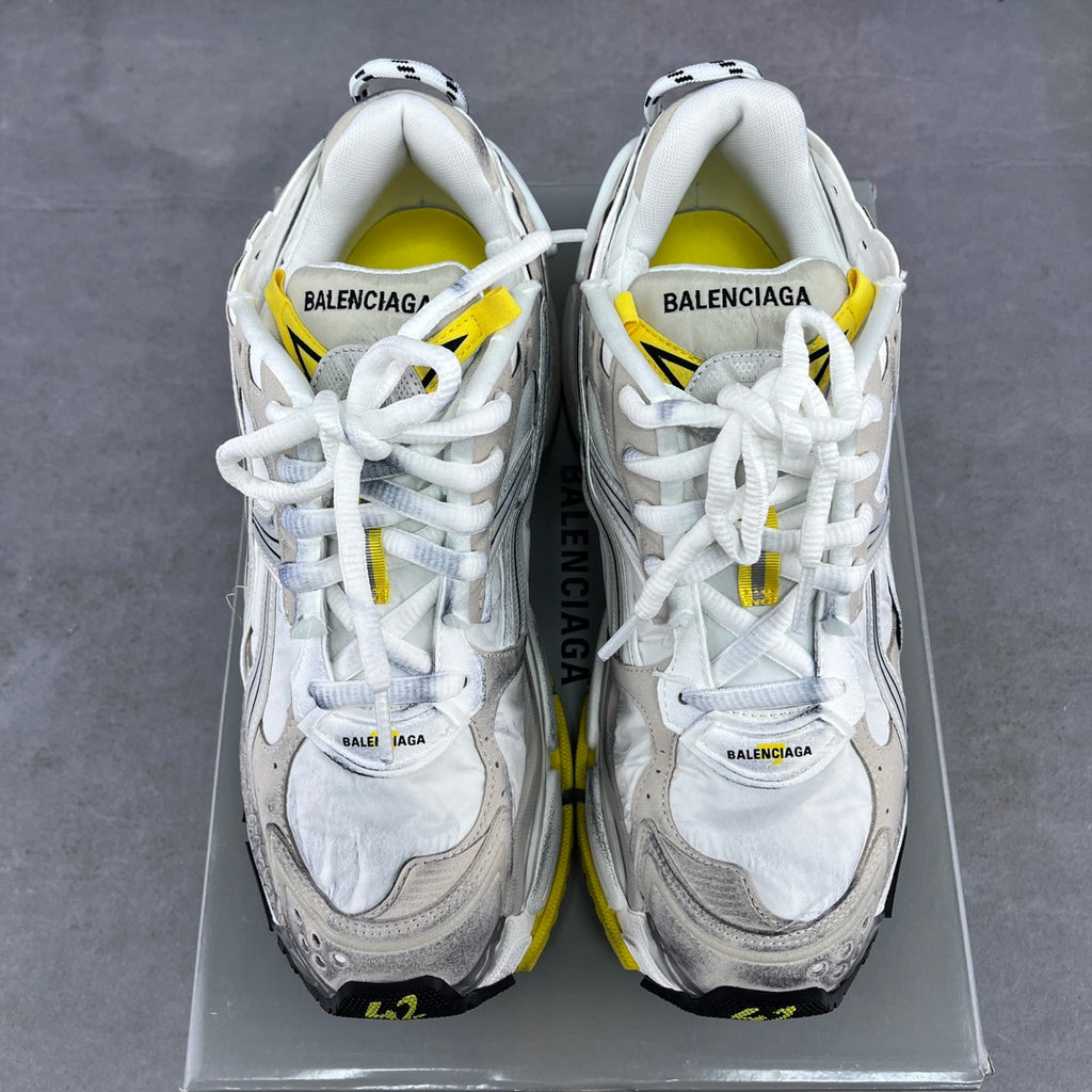 Pair of white lace-up sneakers with Balenciaga branding on tongues and yellow accents.