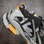 Side and sole view of black and gray sneakers with orange accents and logo.