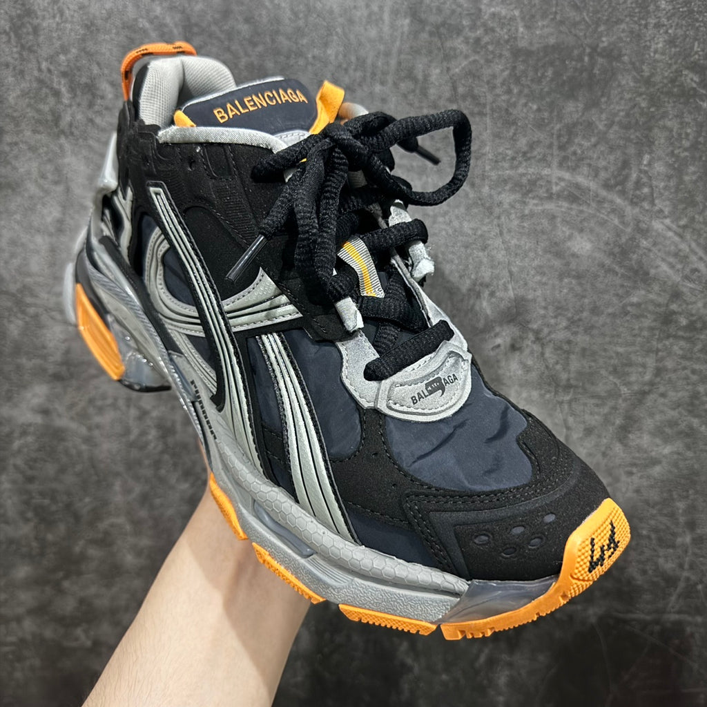 Black, gray, and orange chunky lace-up sneakers with Balenciaga heel text.