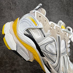 Balenciaga unisex sneakers angled side view, white upper with gray overlays and yellow trim