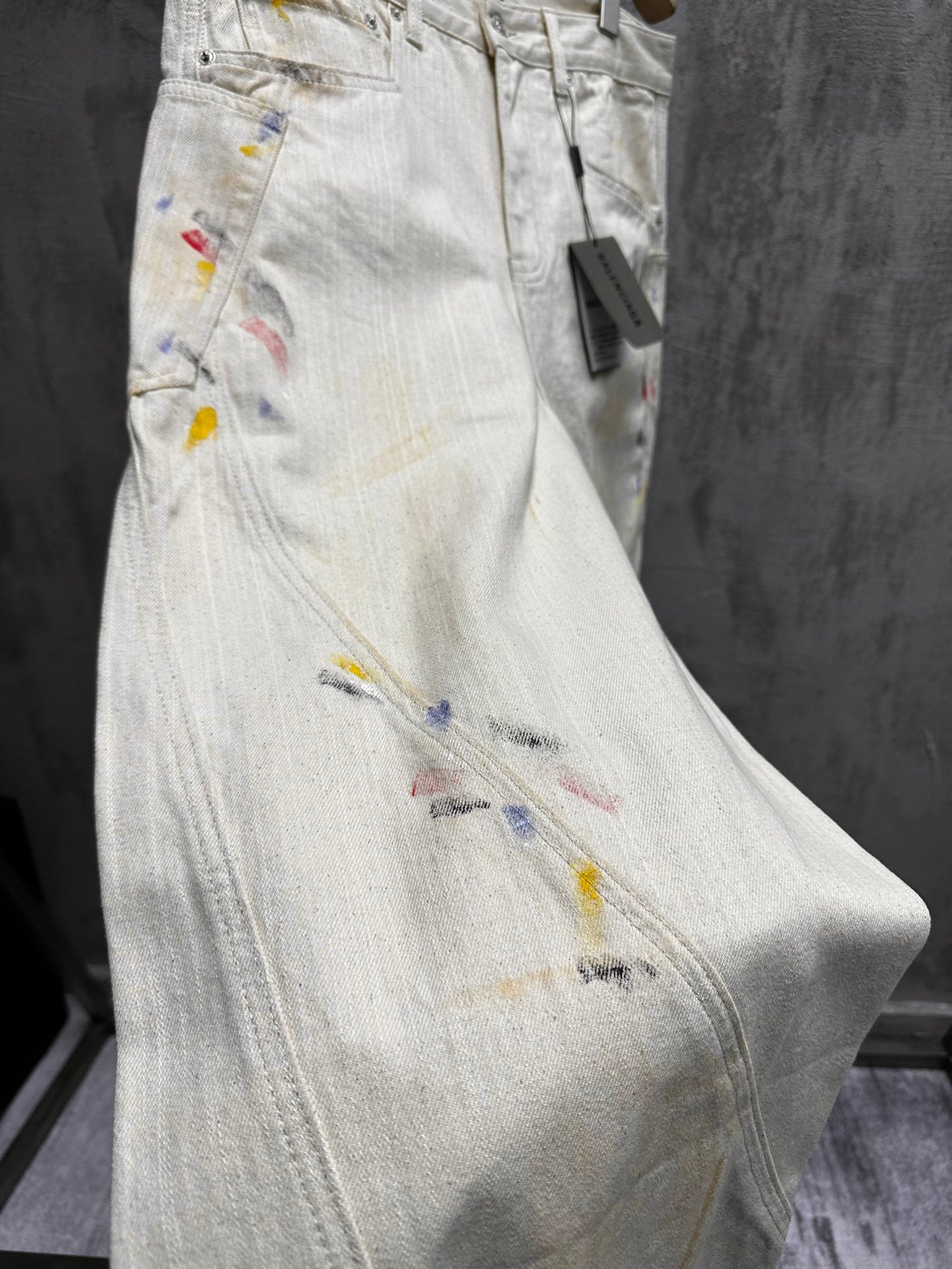 Balenciaga pants, light wash denim with colorful paint splatter, close-up of thigh and pocket