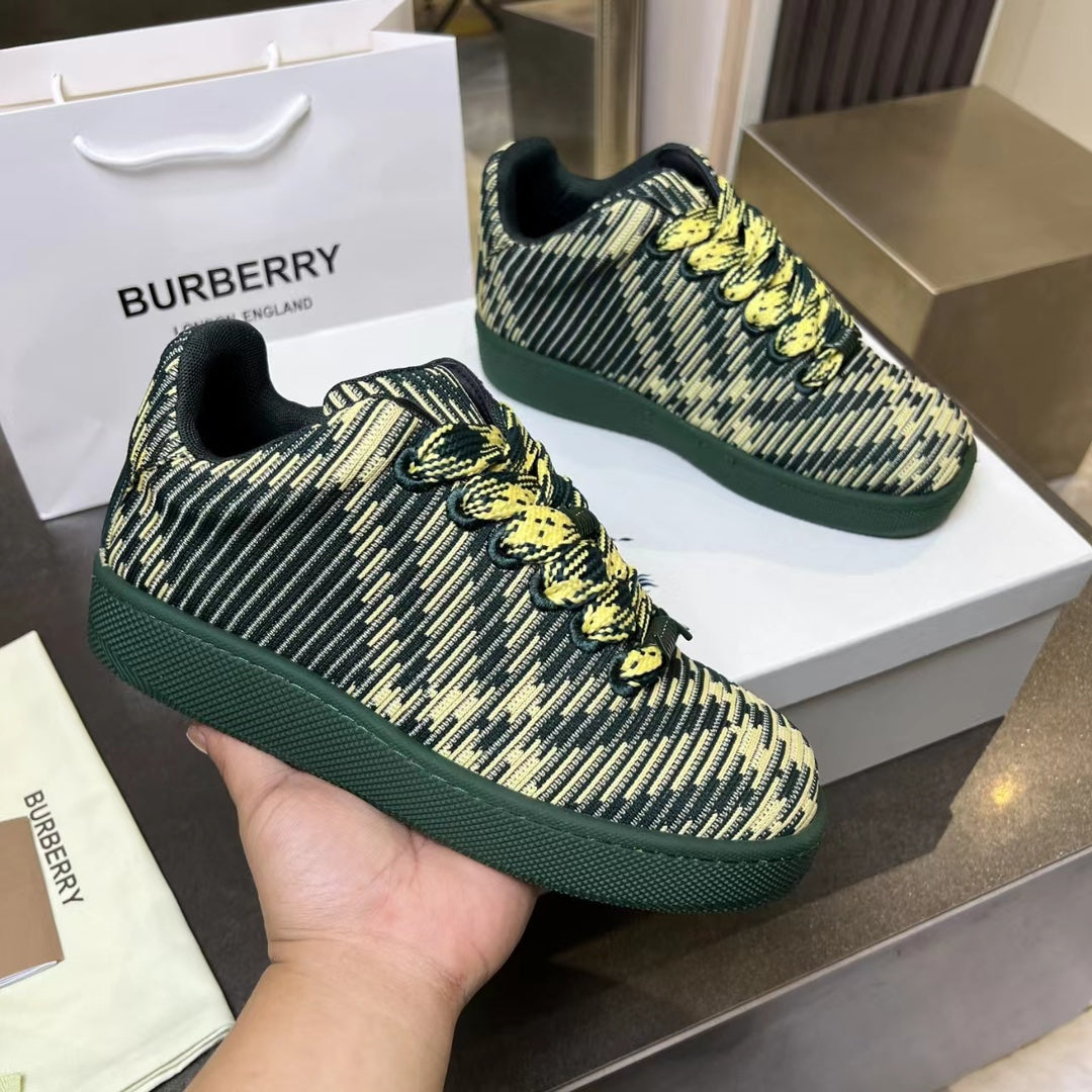 Burberry knit sneakers in dark green with yellow pattern, held up by a hand