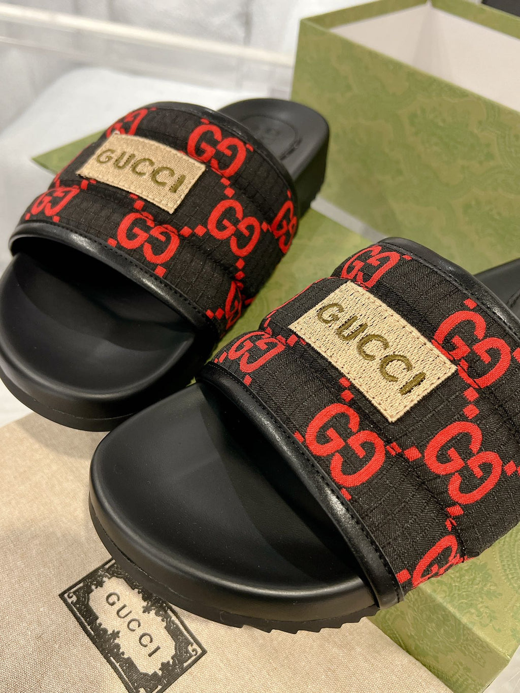Black Gucci slide sandals with red GG web strap and beige logo patch