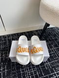 White slide sandals with orange logo strap and cushioned footbed.