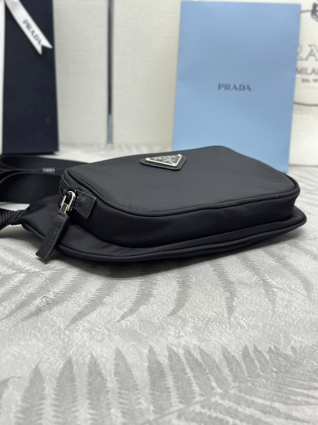 Black crossbody bag with top flap and triangular logo plaque