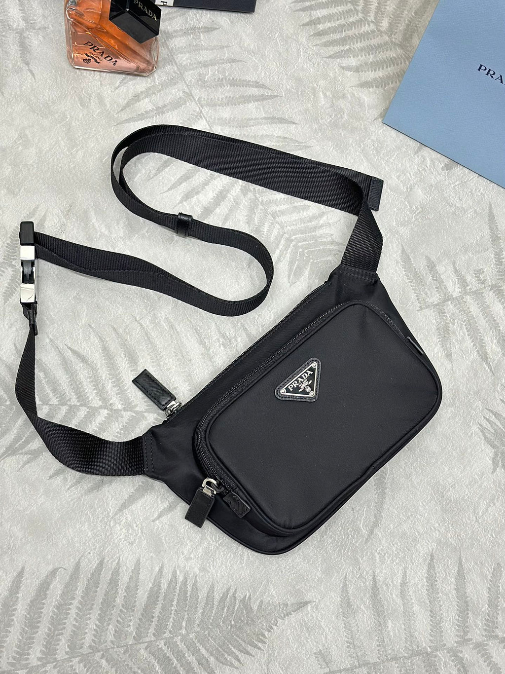 Black crossbody bag with adjustable strap and front logo patch, zippered top