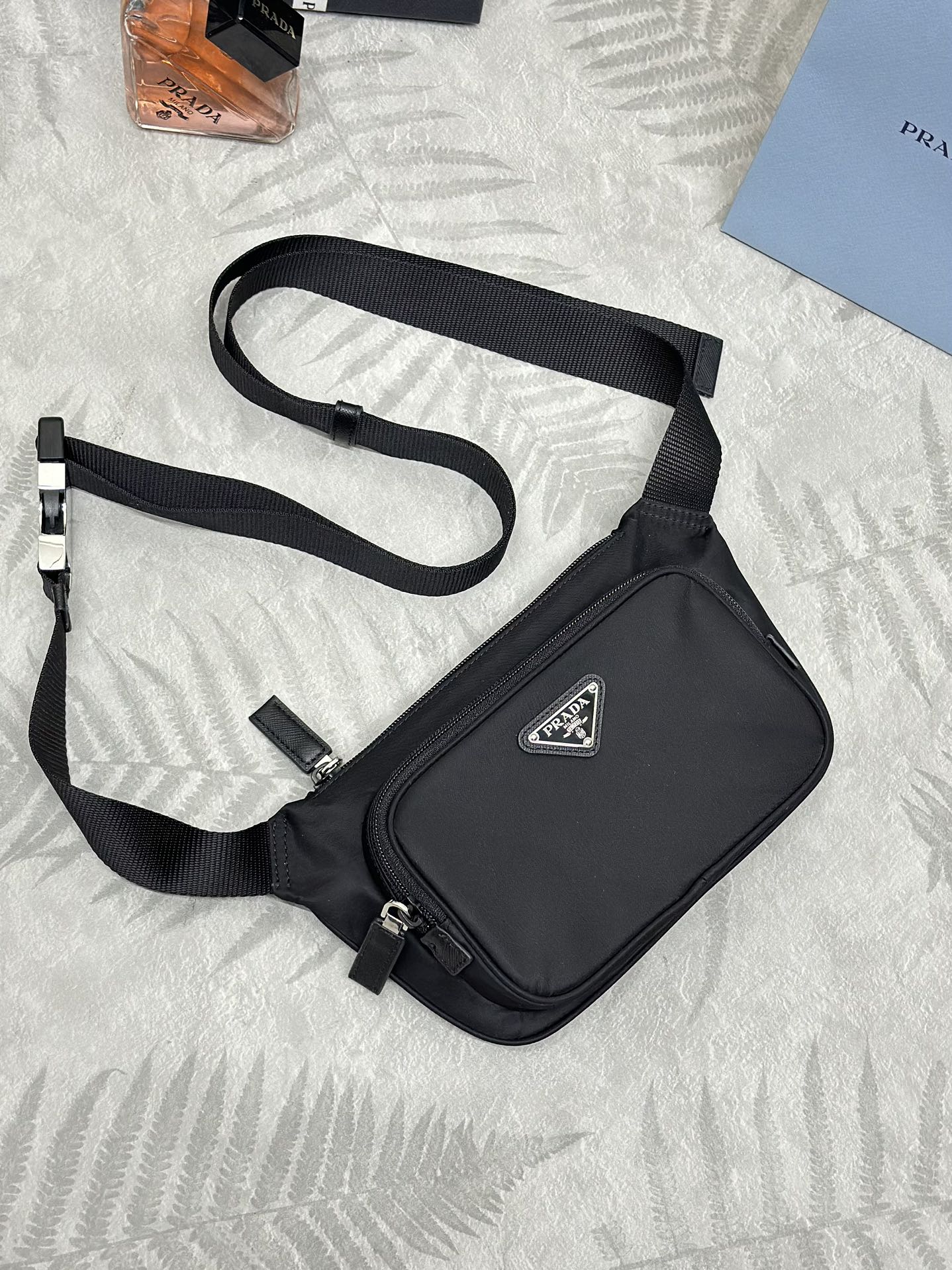 Black crossbody bag with adjustable strap and front logo patch, zippered top