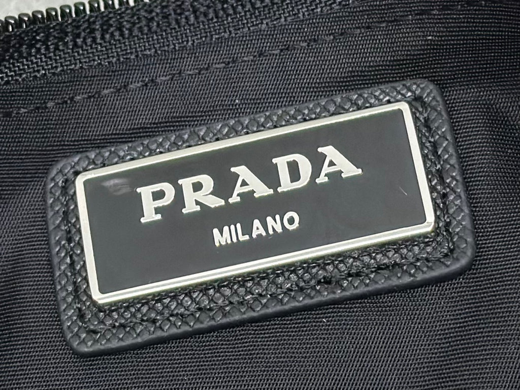 Black logo patch with PRADA MILANO metal plate on crossbody bag
