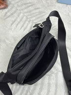 Black crossbody bag shown from side with dual zippers and front pocket