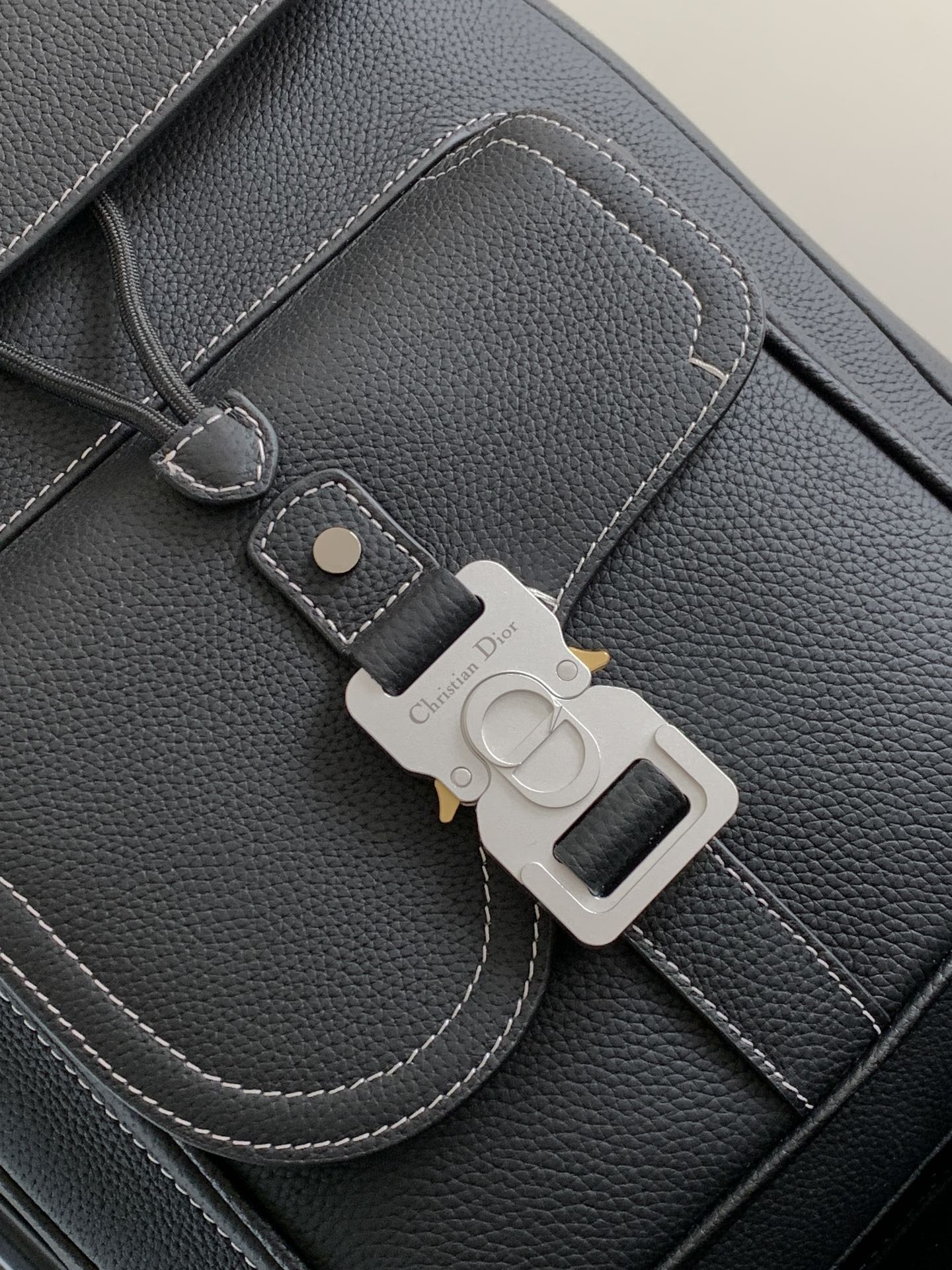 Black leather backpack close-up with stitched pocket and keychain clip
