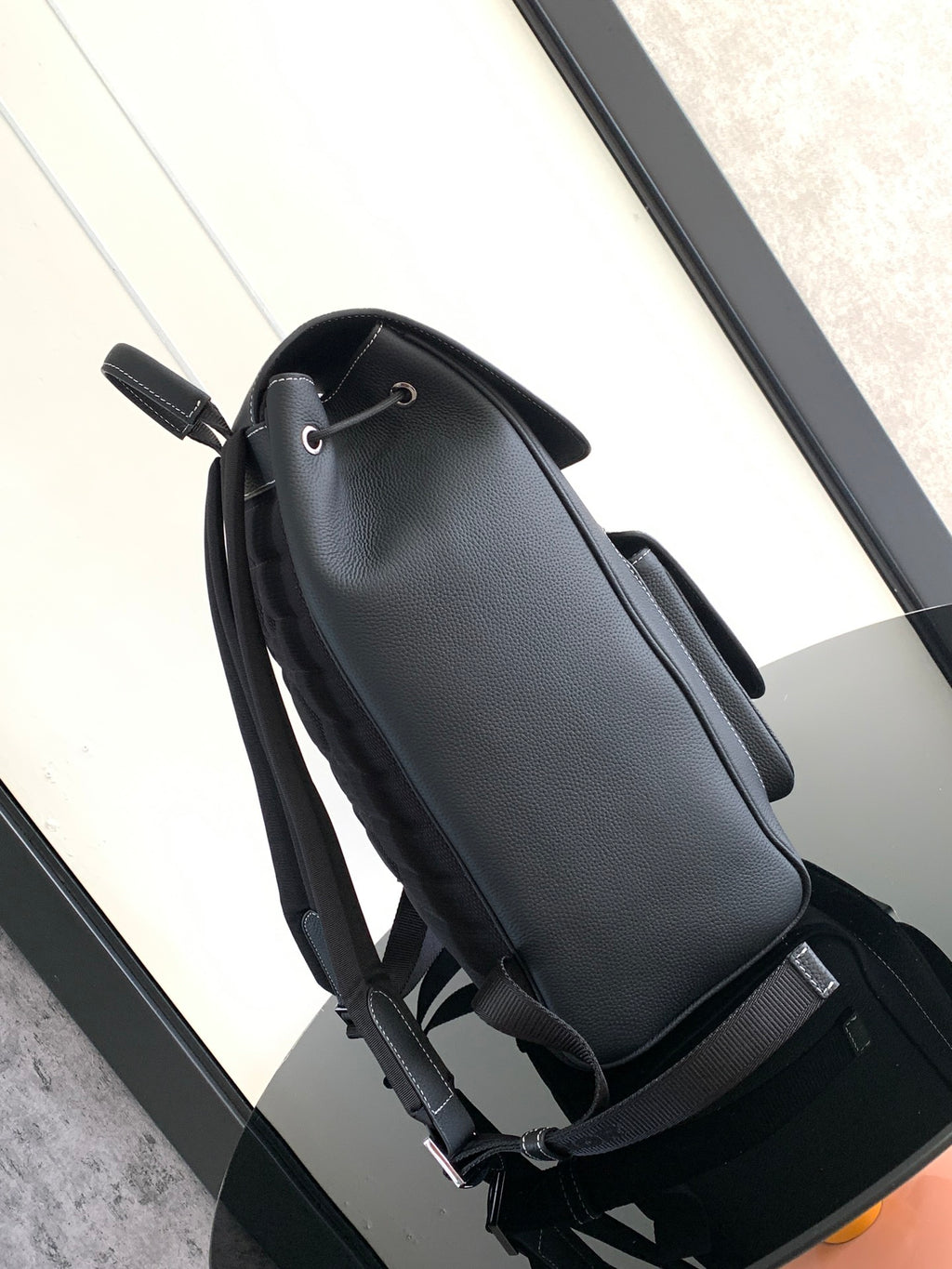 Black leather backpack with top handle, adjustable straps, and side tie detail