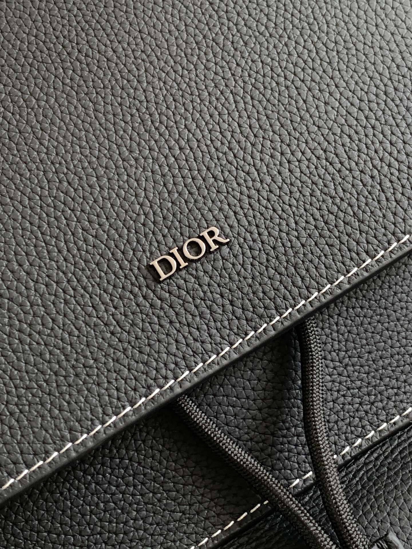 Black leather backpack detail with “DIOR” embossing and contrast stitching