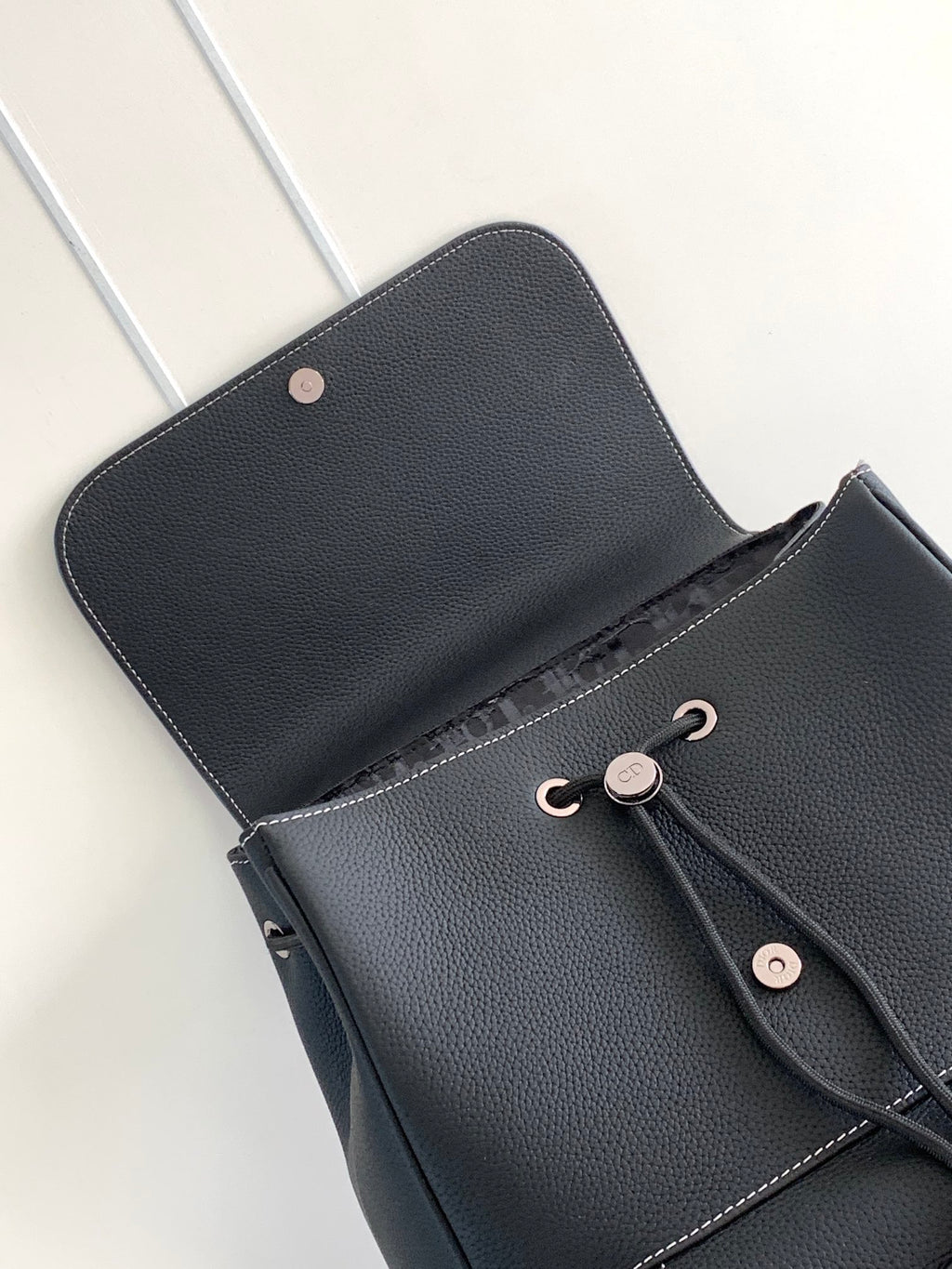 Black leather backpack with snap-button front pocket and hanging strap tab