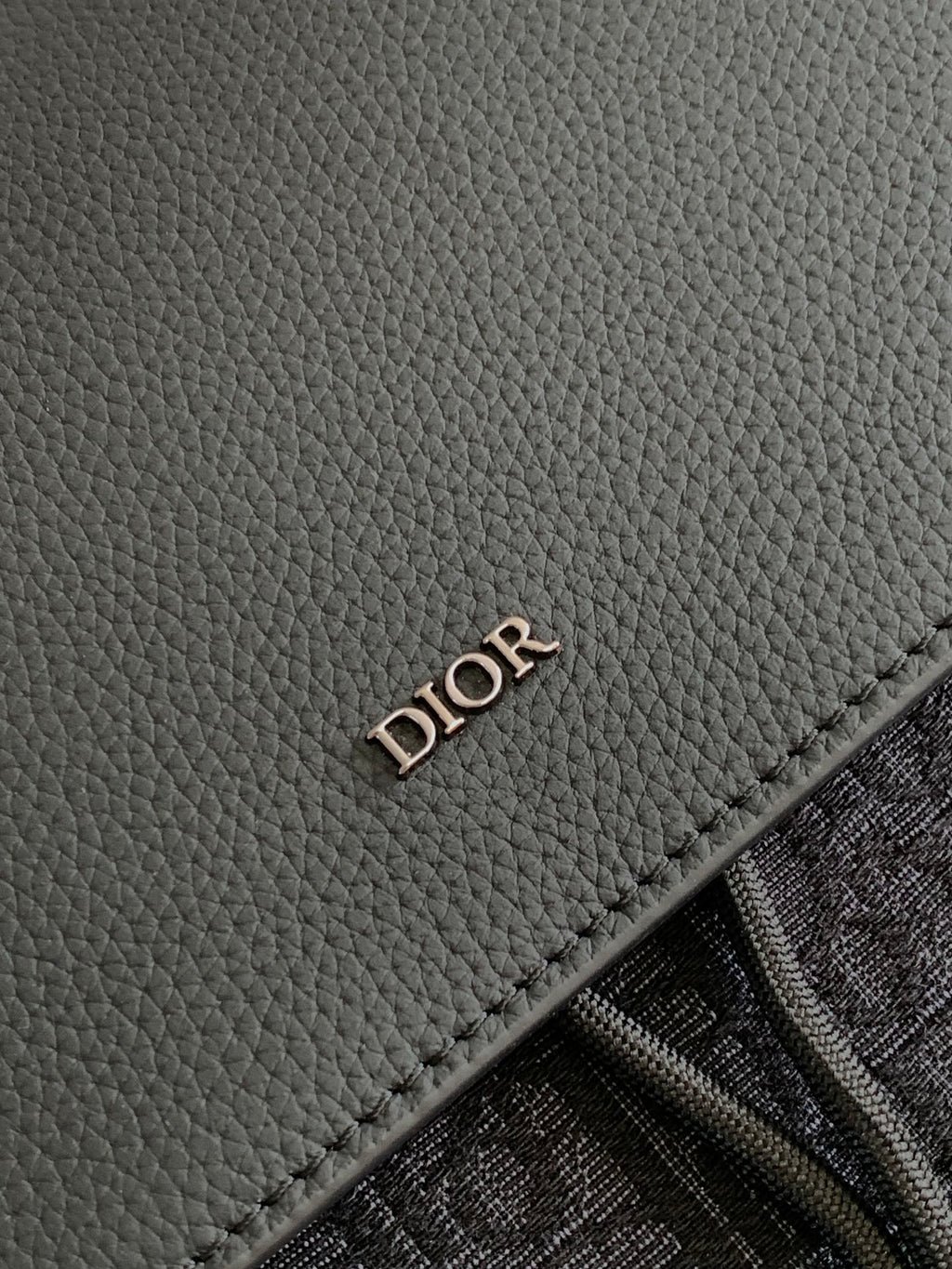 Dior men’s leather backpack panel with embossed “DIOR” stamp and stitched edge