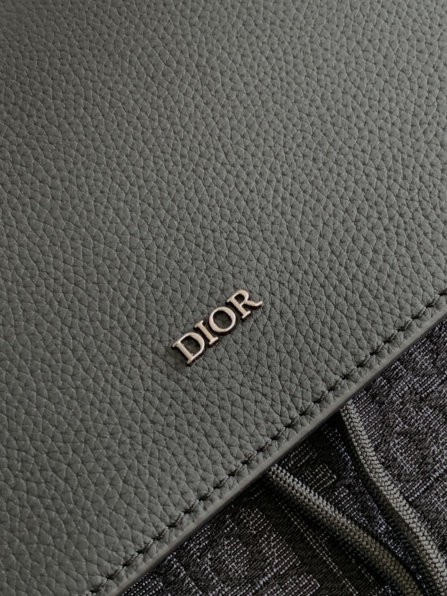 Dior men’s leather backpack panel with embossed “DIOR” stamp and stitched edge