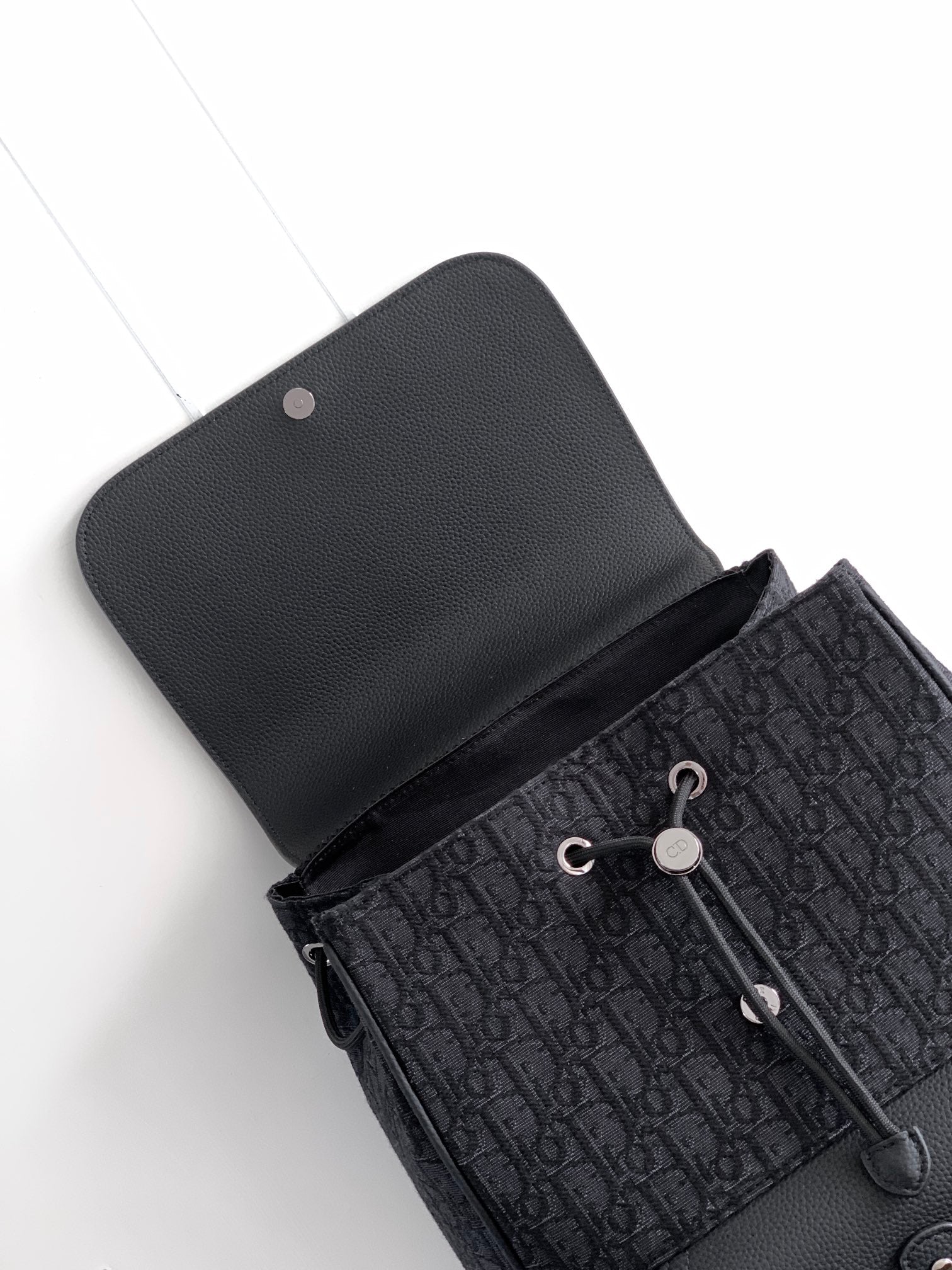 Dior bag top view, dark monogram pattern with snap-flap and leather trim