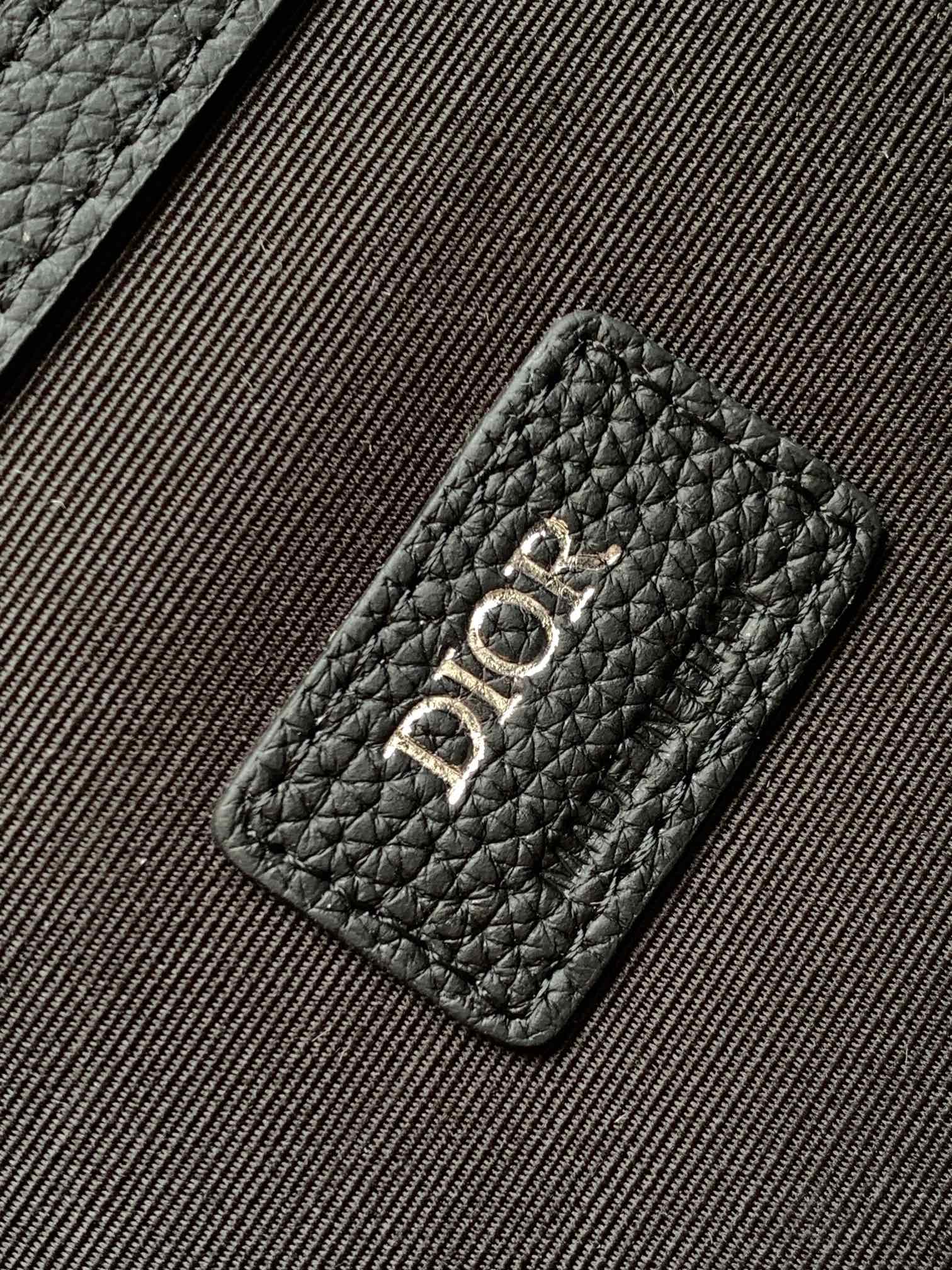 Dior men’s leather patch with embossed “DIOR” lettering on textured monogram panel