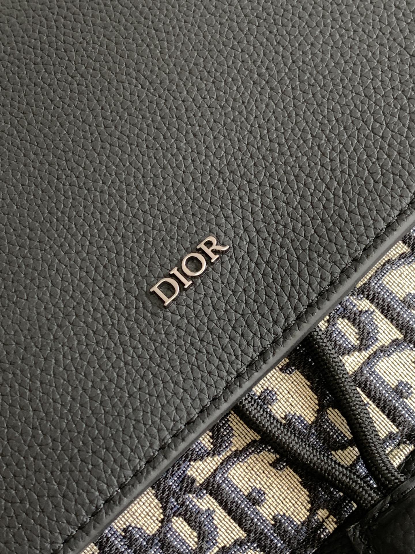 Dior backpack logo on black leather flap with navy-and-cream Oblique canvas border