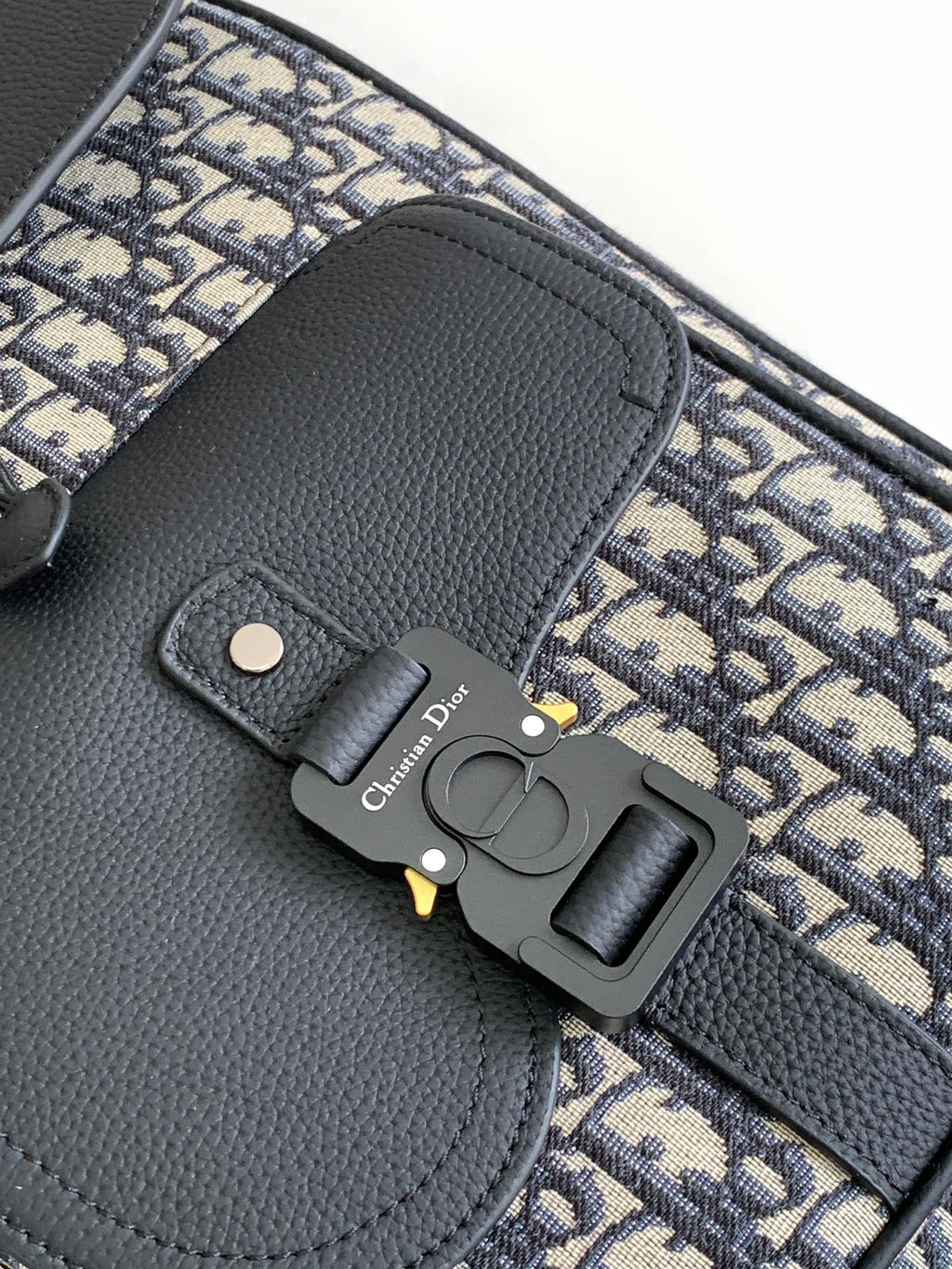 Dior backpack front detail, black leather flap with metal clasp and Oblique canvas trim
