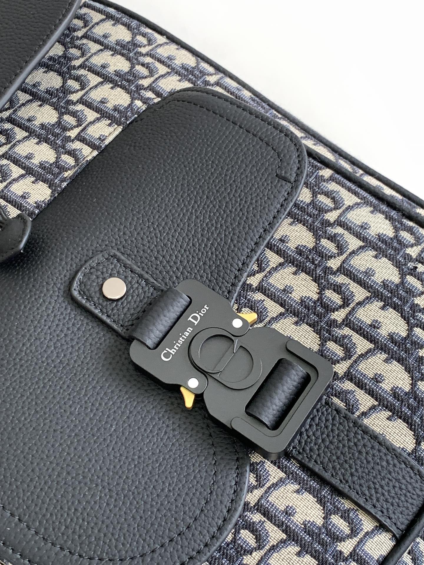 Dior backpack front detail, black leather flap with metal clasp and Oblique canvas trim