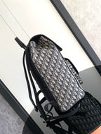 Dior backpack side view with navy-and-cream monogram canvas and black shoulder straps