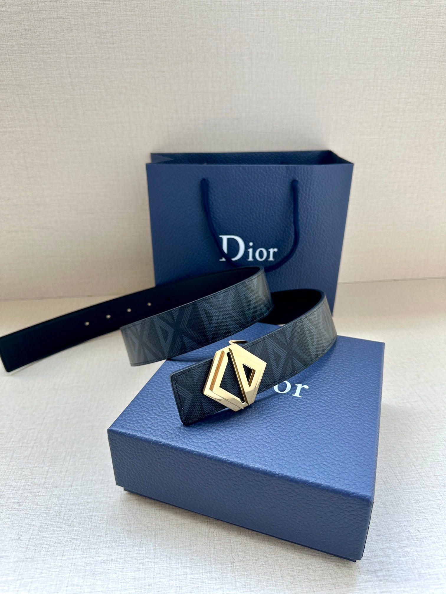 Dior belt on blue box, dark patterned strap with gold-tone LV buckle