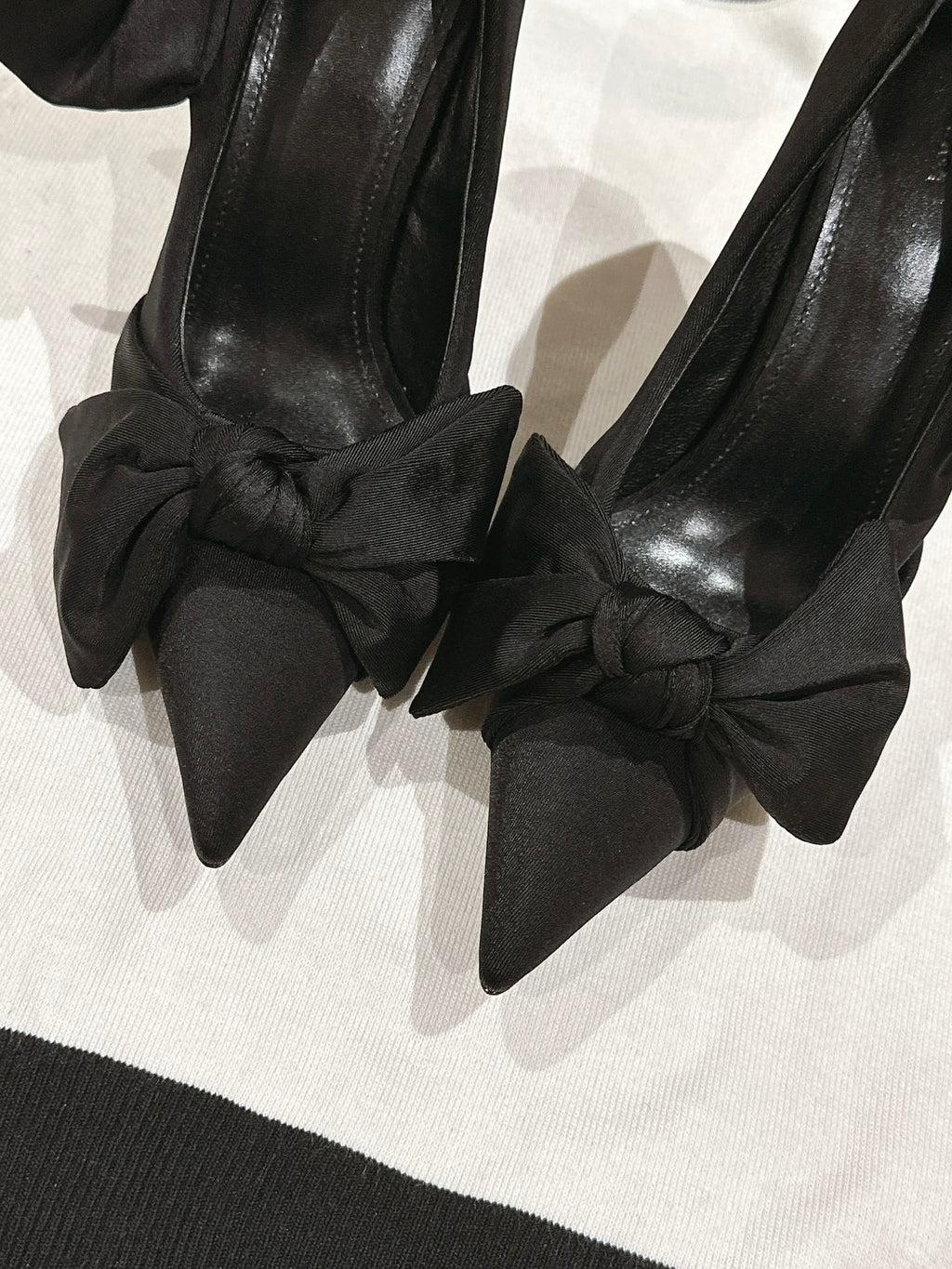 Close-up of black bow-tied high-heel sandals with pointed toe