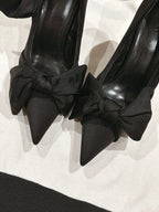 Close-up of black bow-tied high-heel sandals with pointed toe
