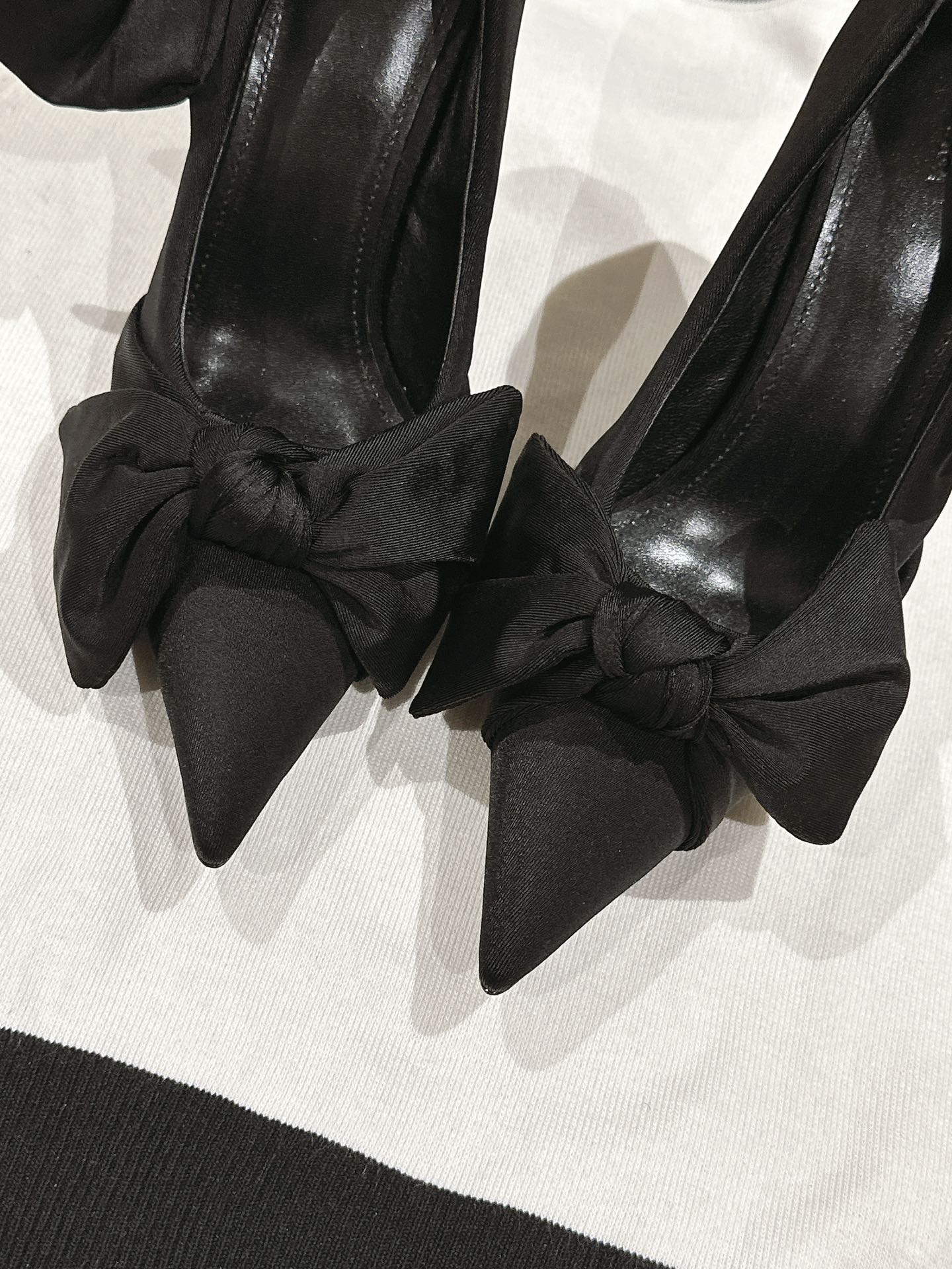 Close-up of black bow-tied high-heel sandals with pointed toe