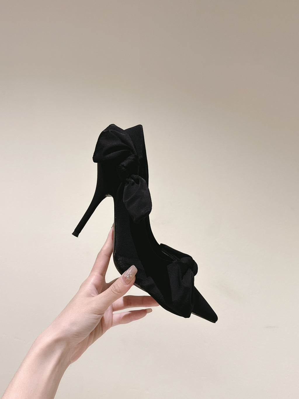 Single black bow-tied heeled sandal with slim stiletto heel held up