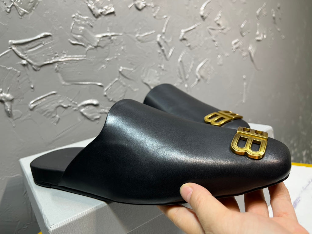 Black sandal held in hand, featuring gold BB logo on the front strap.