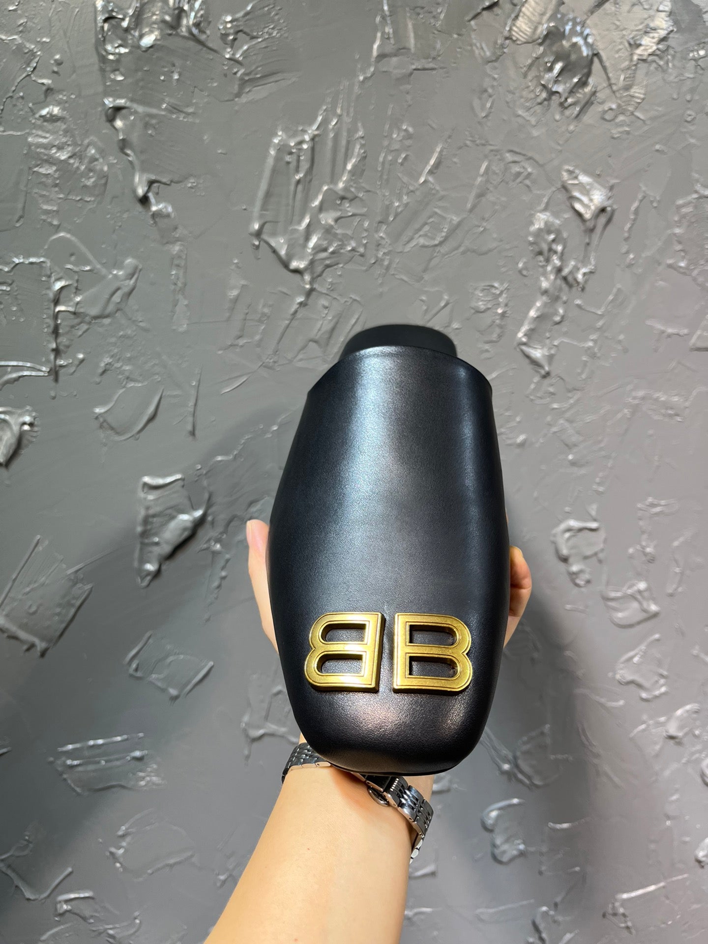 Black slide sandal back view with gold BB logo centered on the heel area.