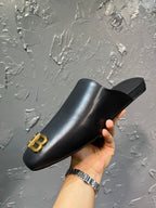Black slide sandal held up with gold BB logo on the front strap.