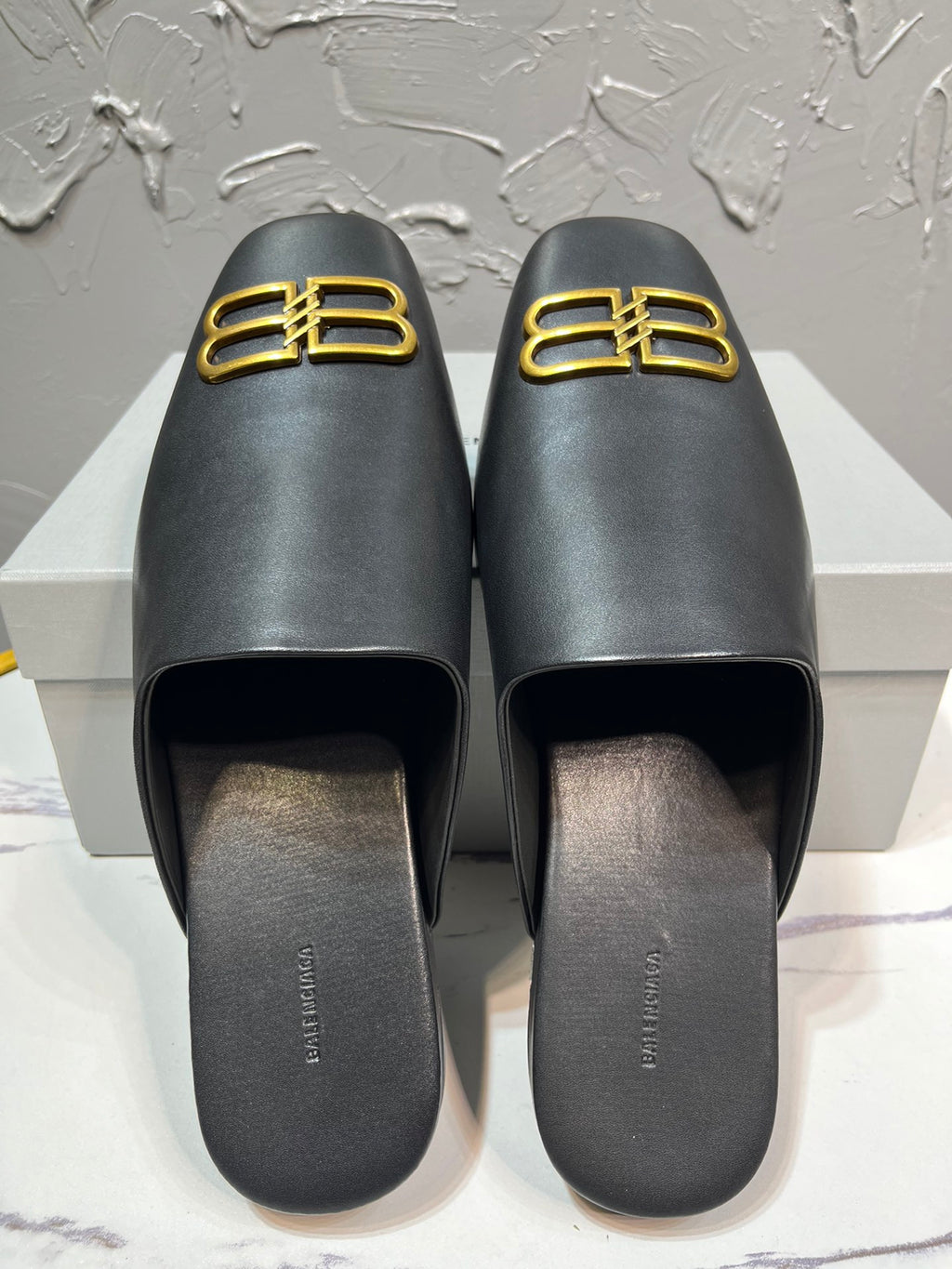 Black leather slide sandals with gold B-logo on front, open toe footbed