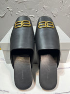 Black leather slide sandals with gold B-logo on front, open toe footbed