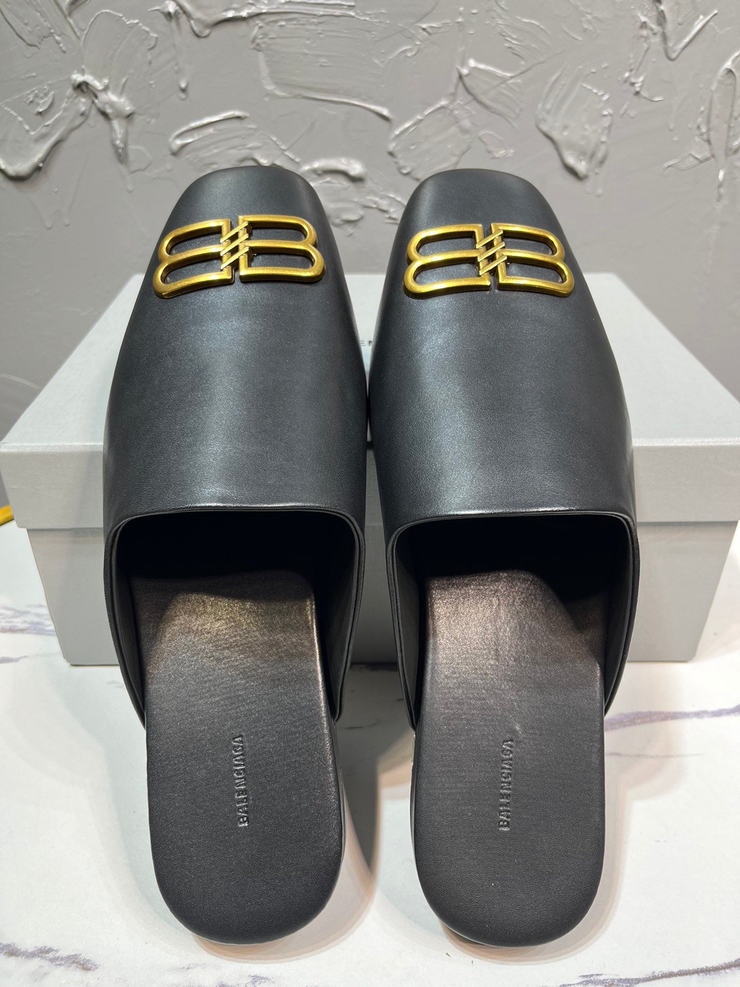 Black leather slide sandals with gold B-logo on front, open toe footbed