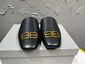 Black leather slide sandals with gold B-logo on front, cushioned footbed