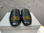 Black leather slide sandals with gold B-logo on front, cushioned footbed