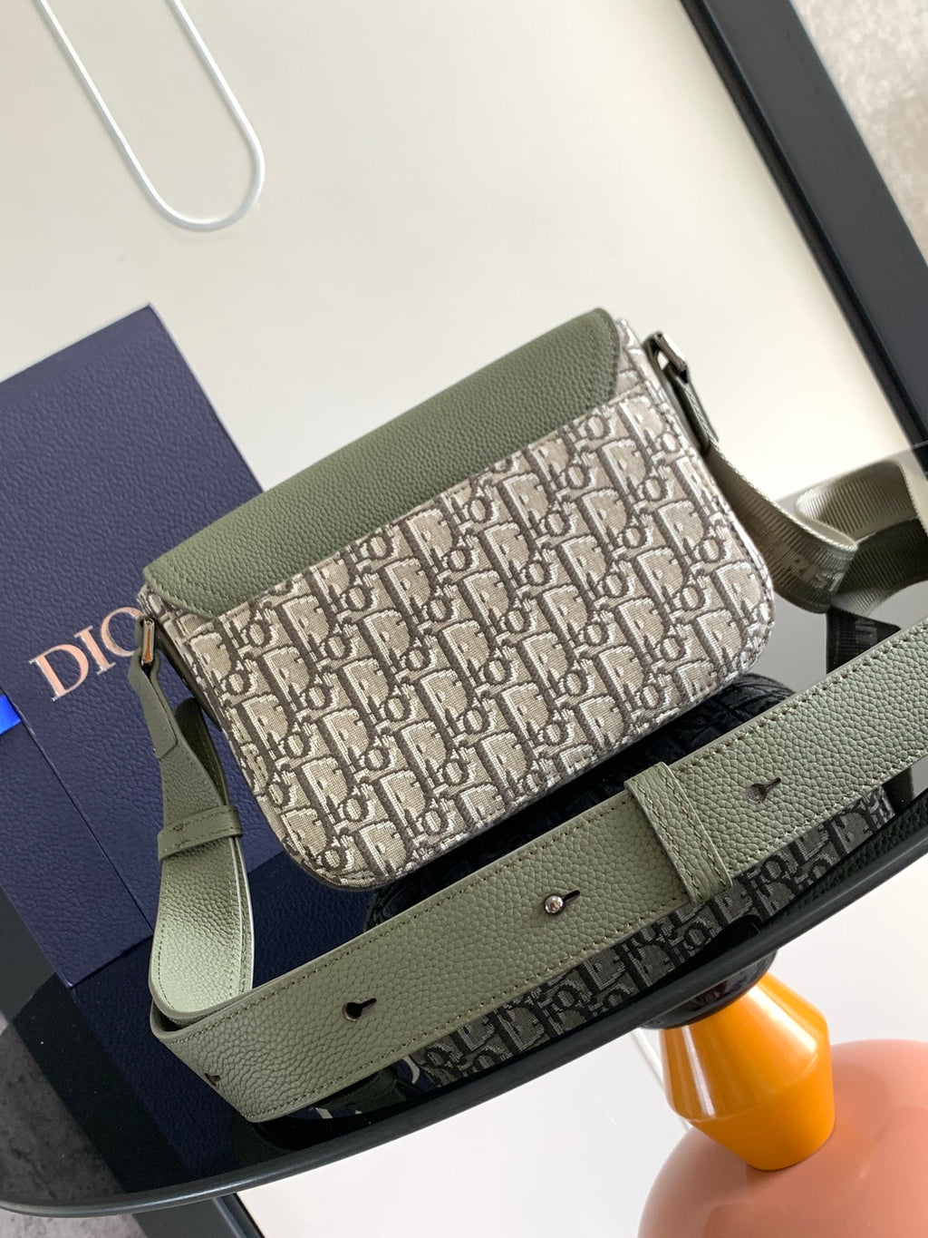 Dior bag with green leather flap and Dior logo canvas body, adjustable shoulder strap.