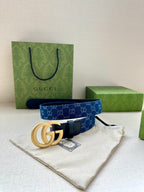Gucci belt with dark blue monogram strap, navy leather ends, and gold double G buckle.