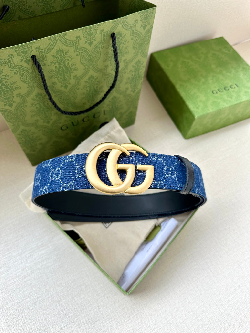 Gucci belt with blue GG-pattern webbing strap and gold-tone GG buckle with keeper.