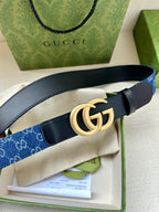 Gucci belt with navy leather strap, blue monogram panel, and gold double G buckle.
