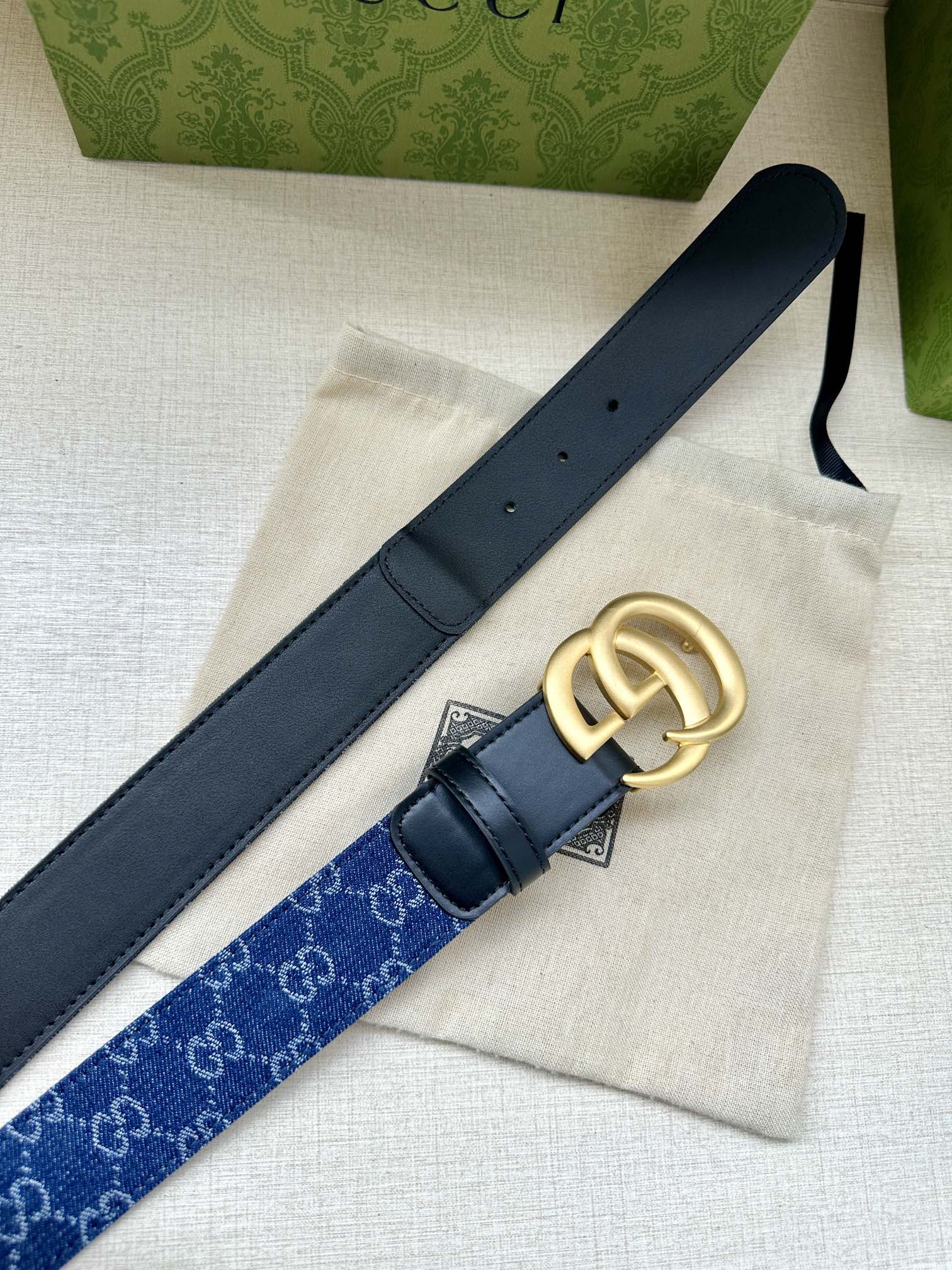 Gucci belt detail: dark blue monogram strap with navy leather backing and gold GG buckle.