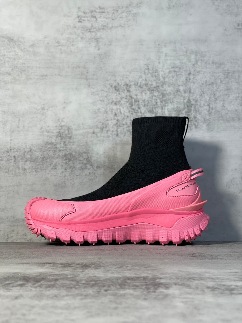 Sock boot sneaker with black elastic knit cuff, pink midsole, chunky tread sole.