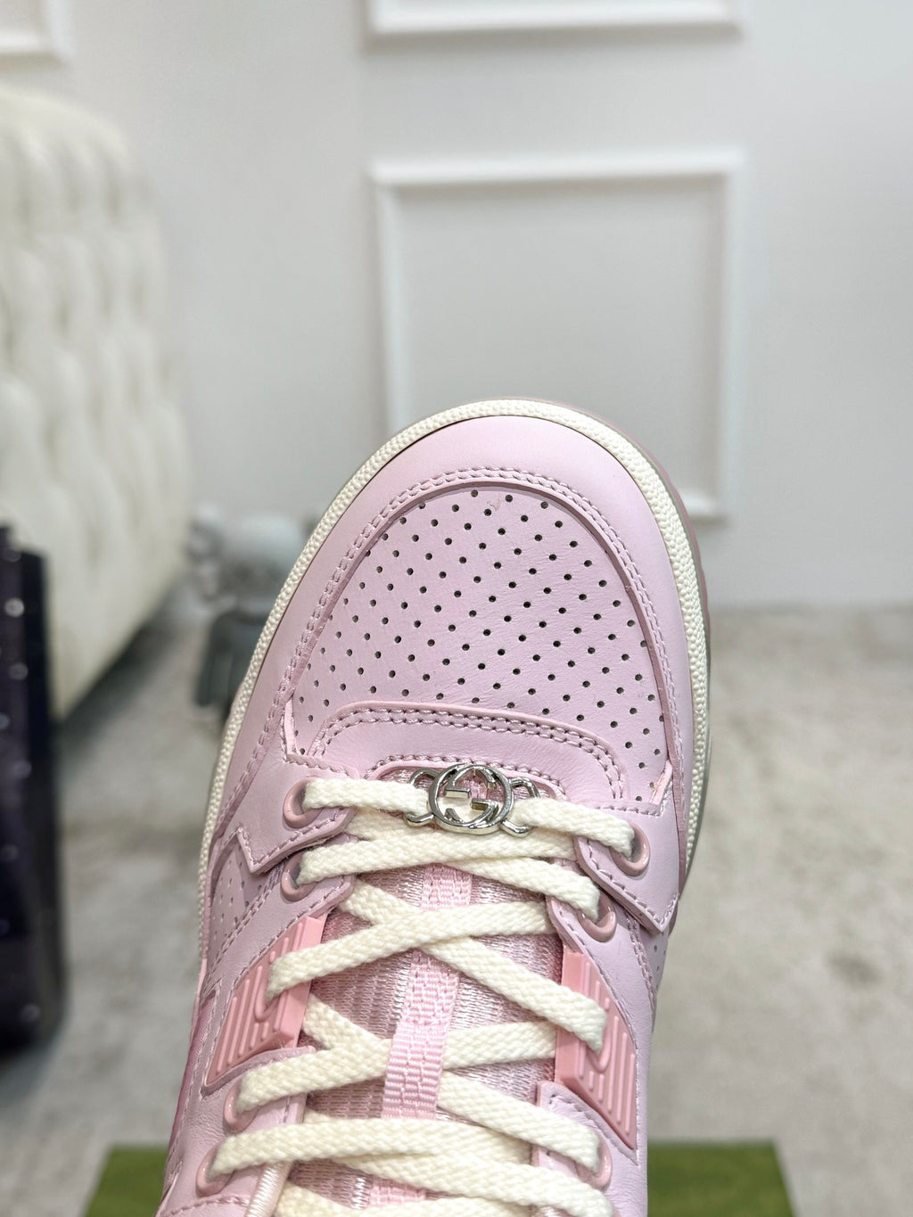 Pink Gucci sneaker toe close-up with perforated leather and lace hardware.