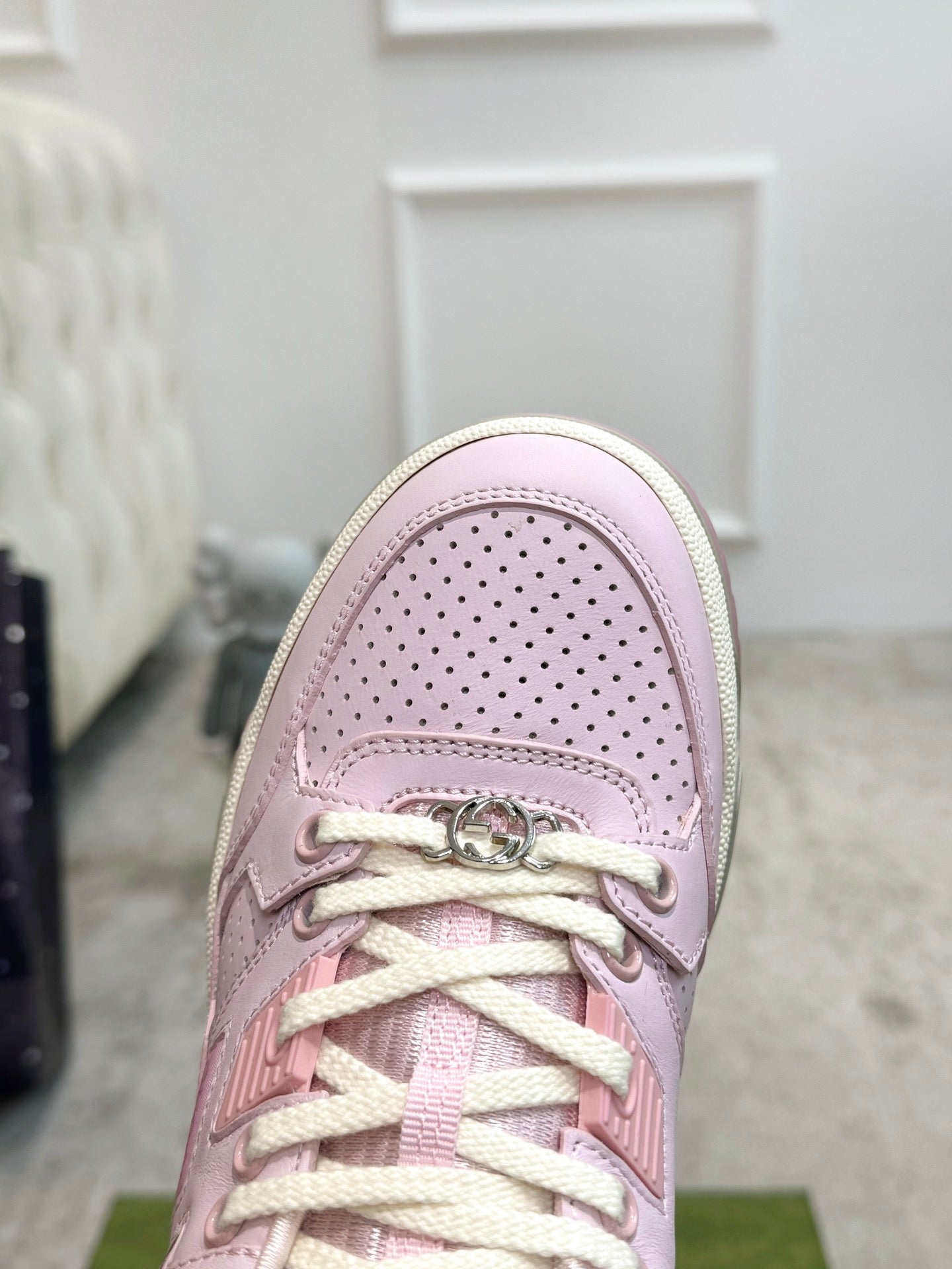 Pink Gucci sneaker toe close-up with perforated leather and lace hardware.